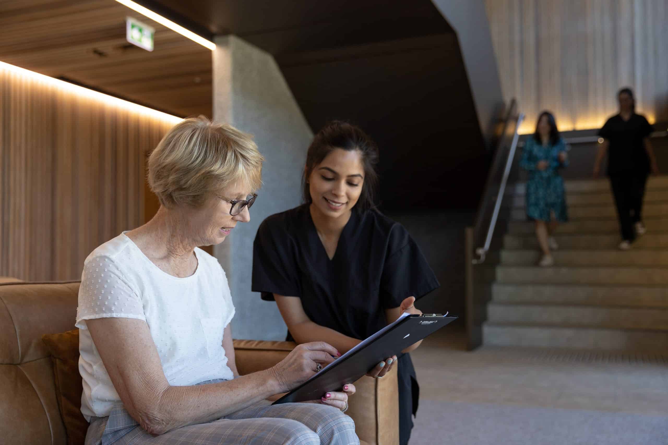 A healthcare professional listening intently to a patient and their friend, illustrating a collaborative and supportive consultation environment.
